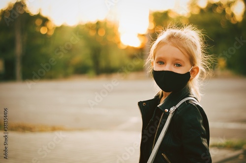Little cute girl wearing black mask outdoors. Covid 19. School. Girl in the park in mask.