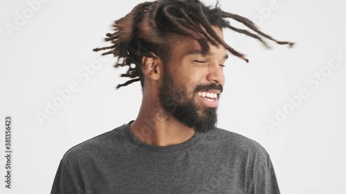 Young african positive man shaking his hair dreadlocks isolated over white wall background