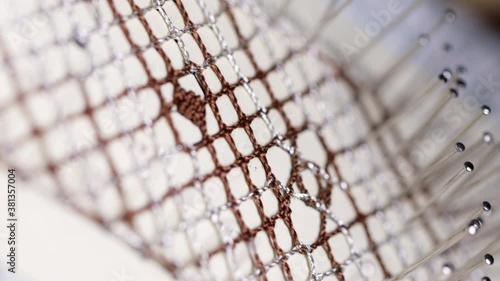Video detail of bobbin lace handcrafting. Woman hands braiding threads to make a pattern.