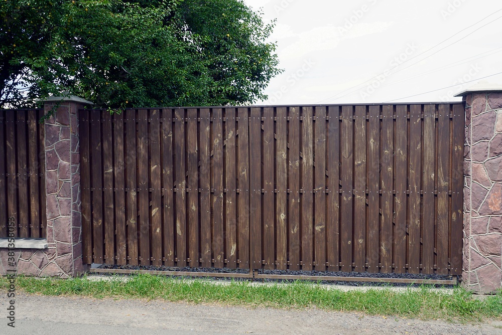 Fototapeta premium one large brown wooden gate on a rural street in green grass