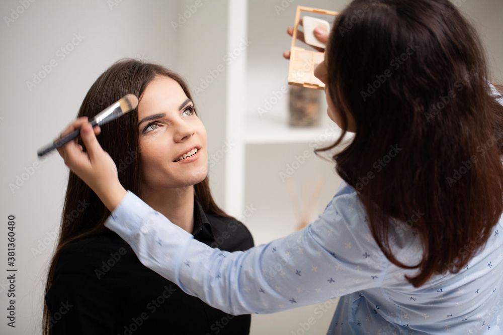 Professional makeup artist working with beautiful young woman