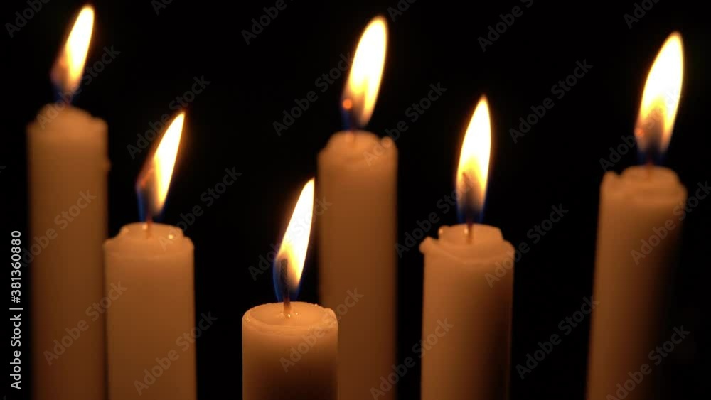 Close up view of candlelight burning in the dark, candles in the dark swayed by the wind breeze. Close up view of candlelight burning in the dark, candles in the dark swayed by the wind breeze.