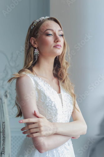 Close-up portrait of a bride in a white wedding dress looks attentively aside