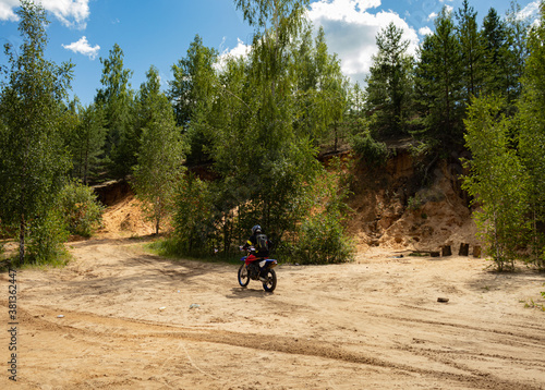 Outfitted biker on off-road motorcycle riding through abandoned sand quarry, extreme hobby. Motocross.