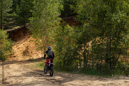 Outfitted biker on off-road motorcycle riding through abandoned sand quarry, extreme hobby. Motocross. © Squirrel Zeta