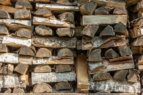 Firewood in woodpile, prepared for Winter. Pile of firewood. The firewood background. A stack of neatly stacked, dry firewood outdoors.