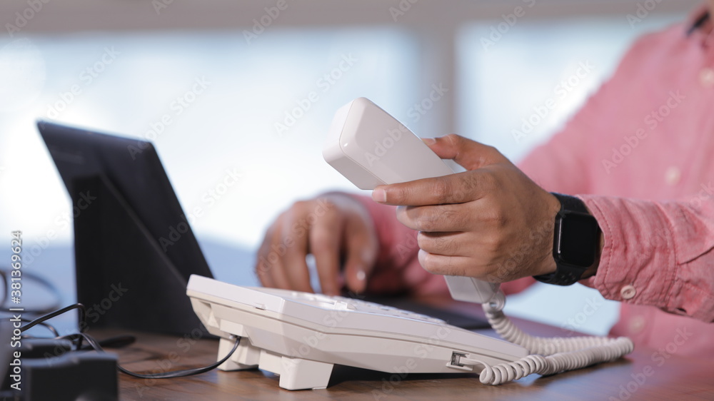 Fototapeta premium Holding handset of the telephone and working in laptop