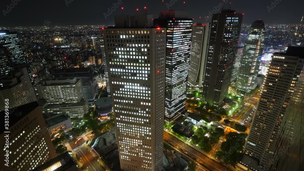 Several tall office towers with glowing lights in window, night time, cars rush on streets between buildings. Aerial time lapse shot of Asian metropolis business district, scenic cityscape Several tall office towers with glowing lights in window, night time, cars rush on streets between buildings. Aerial time lapse shot of Asian metropolis business district, scenic cityscape