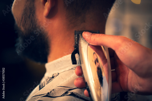 Good looking man visiting barber shop. The barber cuts his hair and trims his beard.