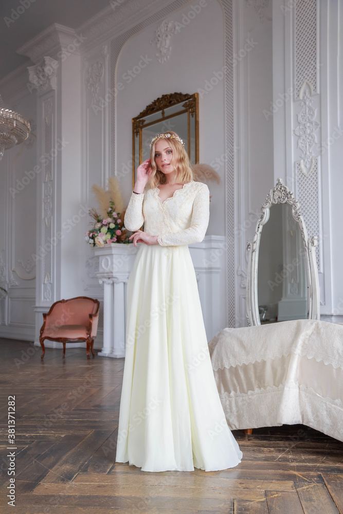 Full-length portrait of a bride in a beautiful wedding dress in the interior.