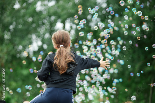 The girl is trying to catch soap bubbles. Lots of soap bubbles.
