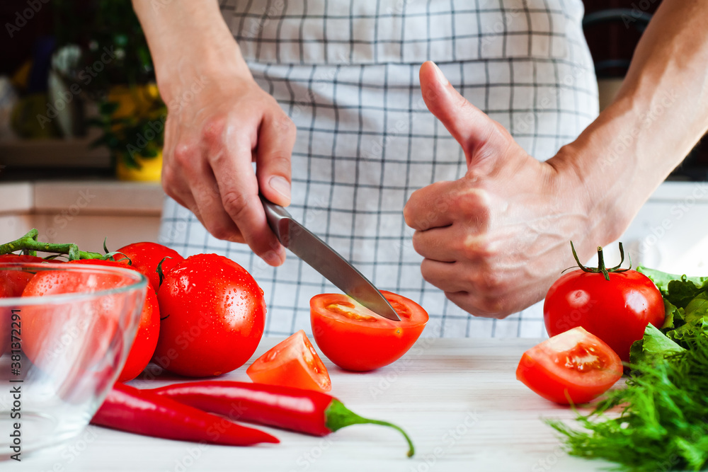 Young man cooking of vegetable salad and male hand showing thumb up. Process of making salad. Healthy food concept. Close-up. Young man cooking of vegetable salad and male hand showing thumb up. Process of making salad. Healthy food concept. Close-up.