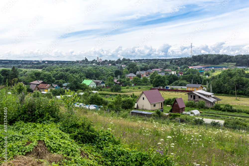 Mid summer. Cottages, green trees and a temple on the horizon. View from the hill. Provincial town of Borovsk in Russia.