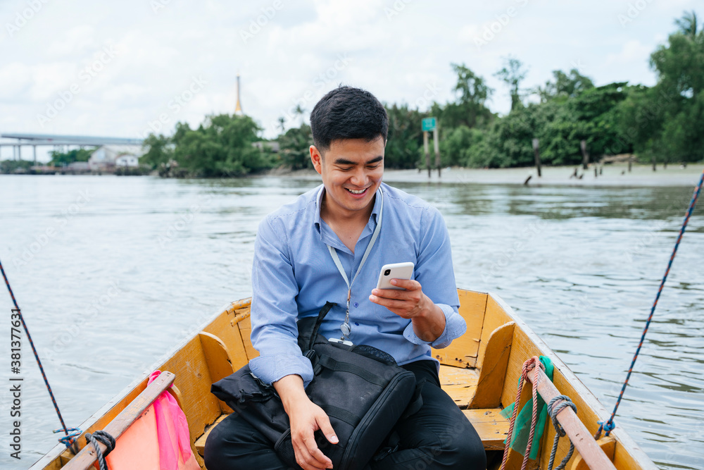 Asian business man using phone and travel by a boat in Bangkok. Asian business man using phone and travel by a boat in Bangkok.