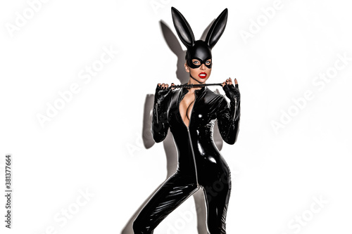 Halloween sexy girl in bunny costume. Sexy blonde beautiful woman posing in latex costume and black bunny mask on white background. Hallooween concept. photo