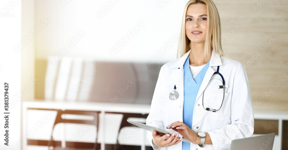 Woman-doctor controls medication history records and exam results while using tablet computer in sunny hospital. Medicine and healthcare concept Woman-doctor controls medication history records and exam results while using tablet computer in sunny hospital. Medicine and healthcare concept