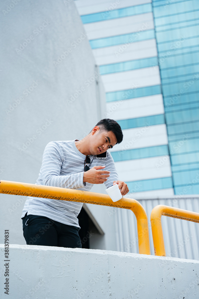 Stylish asian adult man talking on the phone at balcony. Stylish asian adult man talking on the phone at balcony.