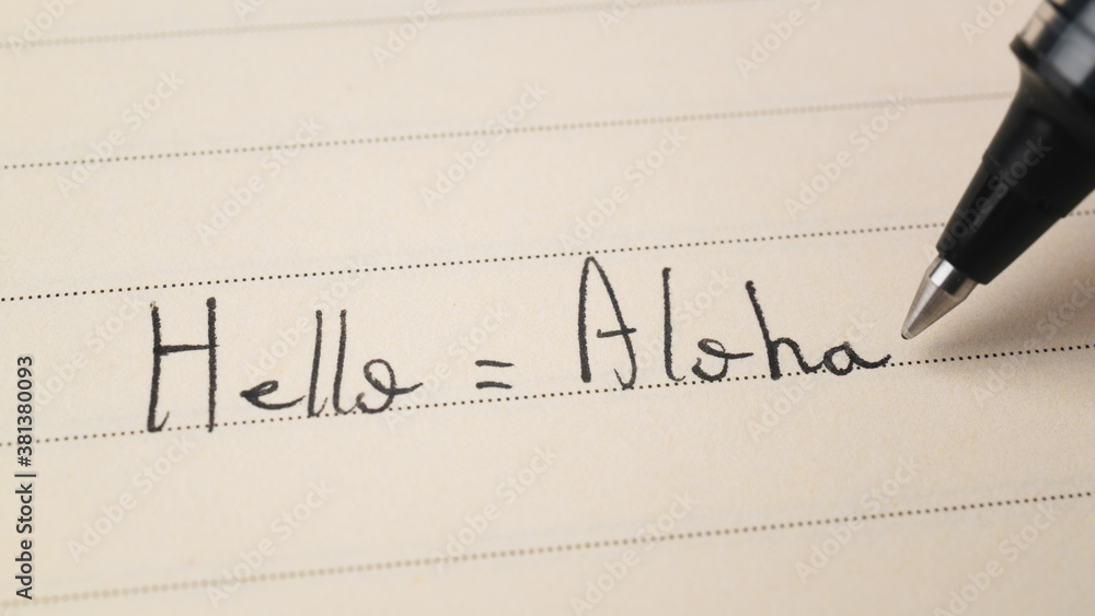 Beginner Hawaiian language learner writing Hello word Aloha for homework on a notebook