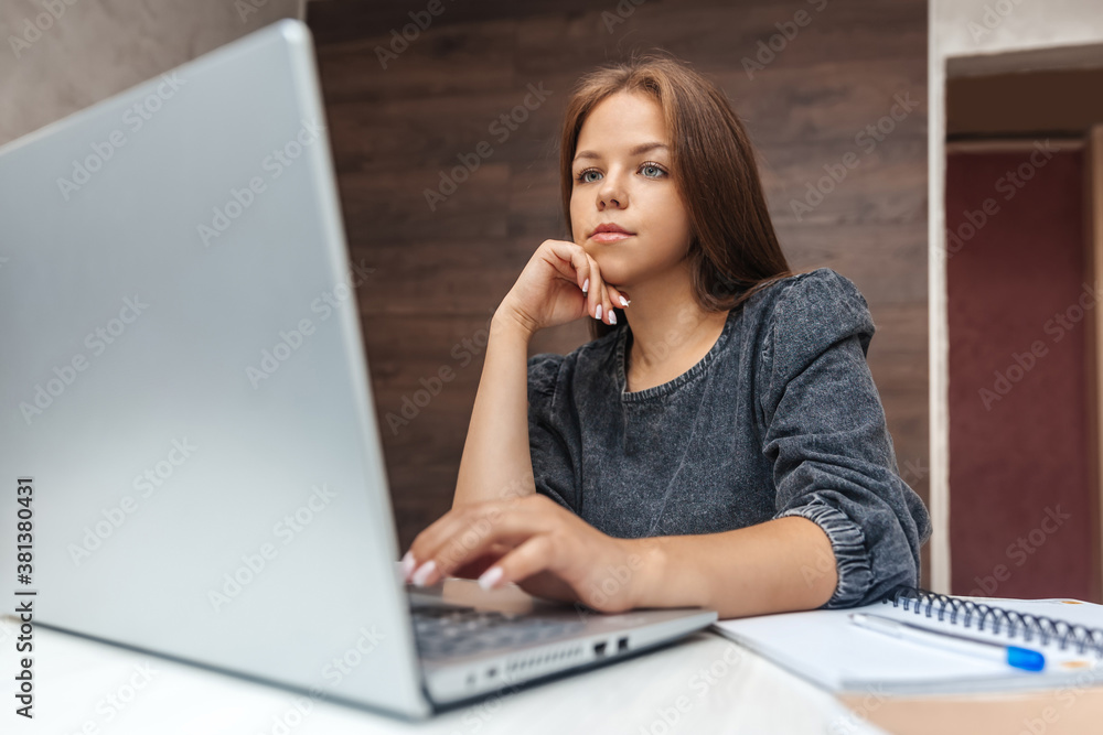 Focused woman working at home at the computer. Serious girl looking at laptop Focused woman working at home at the computer. Serious girl looking at laptop