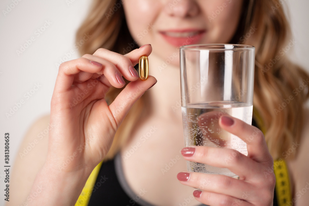Portrait of smiling young woman with Omega 3 fish oil capsule Portrait of smiling young woman with Omega 3 fish oil capsule
