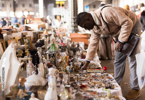 African American man chooses antiques on the flea market