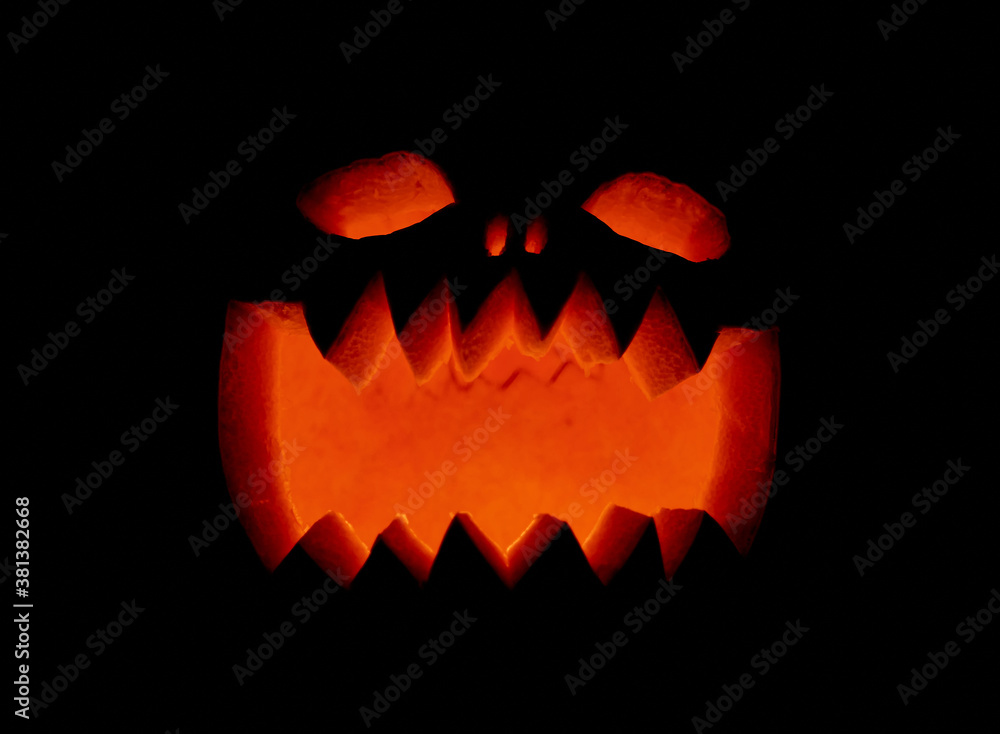 Closeup of the light shining through the carved pumpkin for Halloween in a dark setting