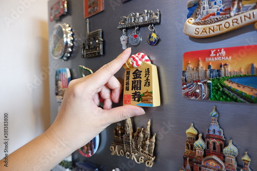 Bild auf Leinwand Putting a new magnet on fridge door, closeup hand