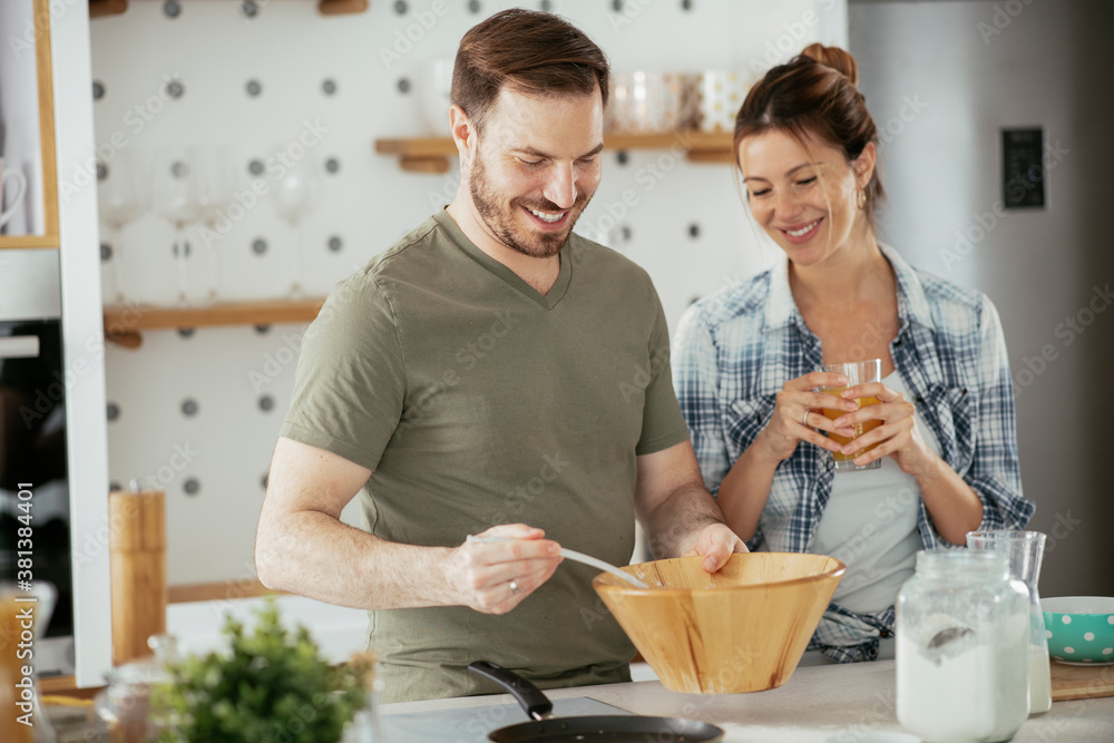 Young couple making pancakes at home. Loving couple having fun while cooking. Young couple making pancakes at home. Loving couple having fun while cooking.