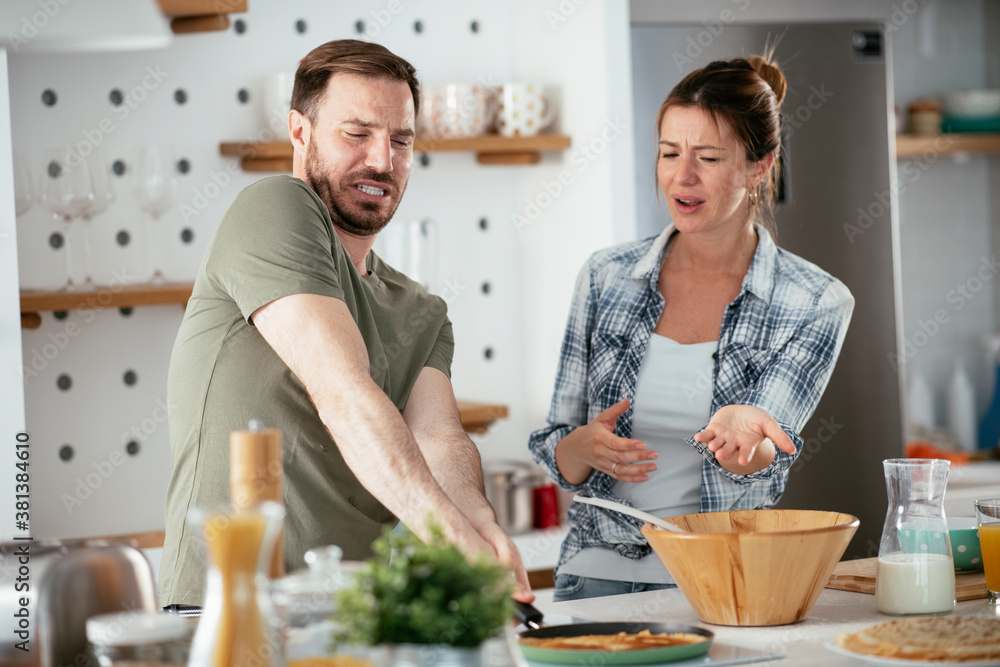 Young couple making pancakes at home. Loving couple having fun while cooking. Young couple making pancakes at home. Loving couple having fun while cooking.