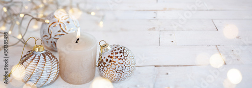 White christmas decoration with candle on vintage wood. Horizontal close-up with golden bokeh and short depth of field. Atmospheric background for christmas greetings. Space for text .