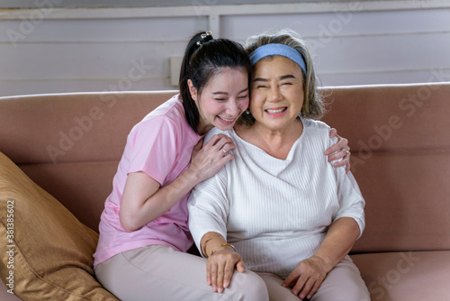Asian young woman take care and  support with hug, that make feel good and smile older mother in living room. family concept
