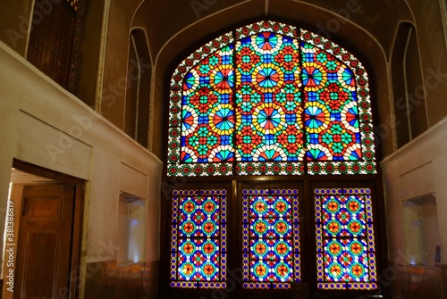 Yazd, Iran. April 10, 2019: The beautiful symmetrical colorful stained glass windows of the Pavilion under the wind catcher at Dolat Abad Garden. UNESCO World Heritage Site. photo