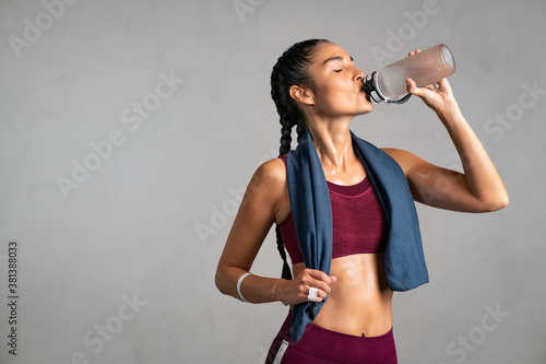 Fototapeta Fit woman drinking from water bottle