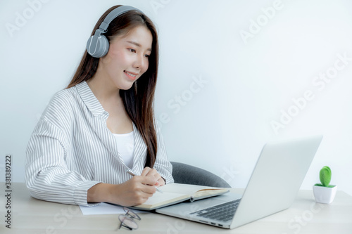 Young woman student taking notes watching laptop study online class video conference education elearning course from home