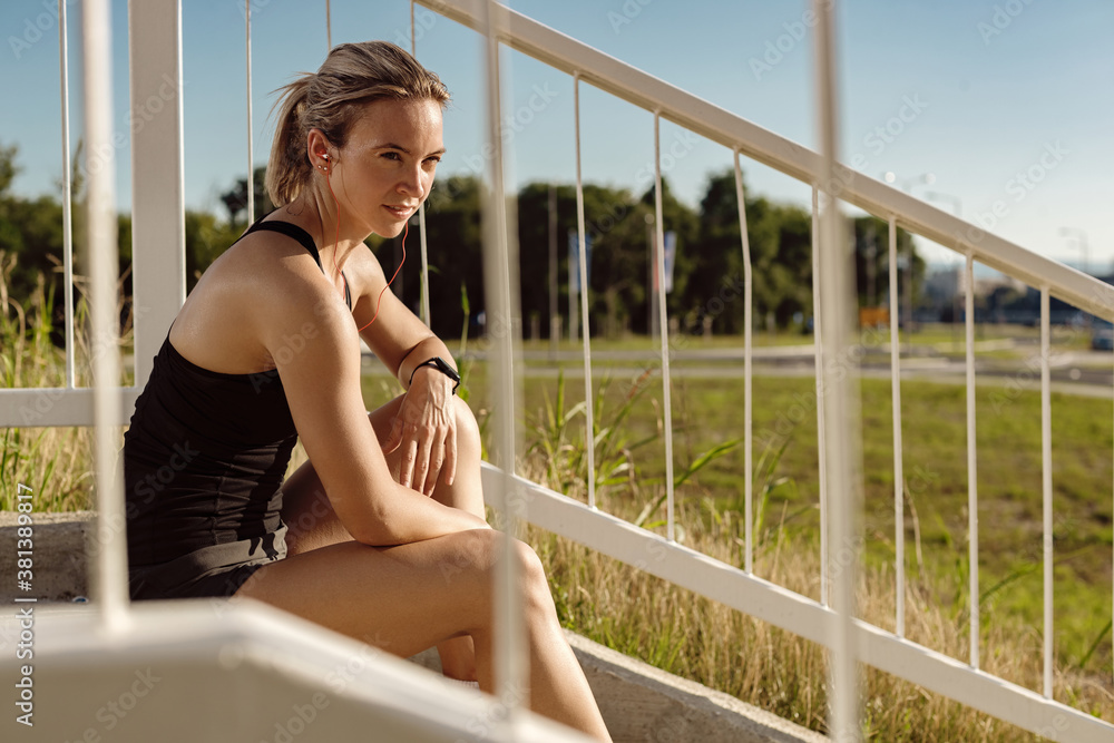 Young athletic woman relaxing on the stairs outdoors.