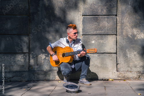 Male street musician playing guitar on the streets of old European city. Horizontal image.