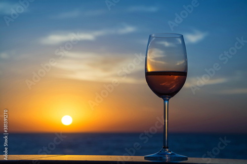 Glass with wine, champagne against background of dawn sky and sea