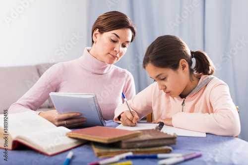 Mother and daughter are doing school homework together at home