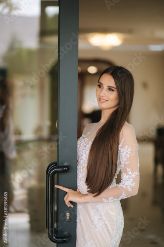 Beautiful young model in evening drees posing to photographer inside big restaurant