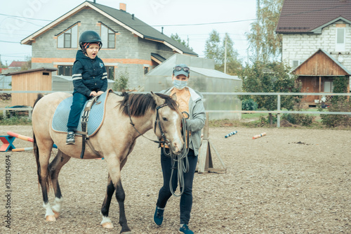 A child with special needs is riding with a close supervision teacher. This is a treatment called Hippotherapy, Life in the education age of disabled children, Happy disability kid concept. quarantine