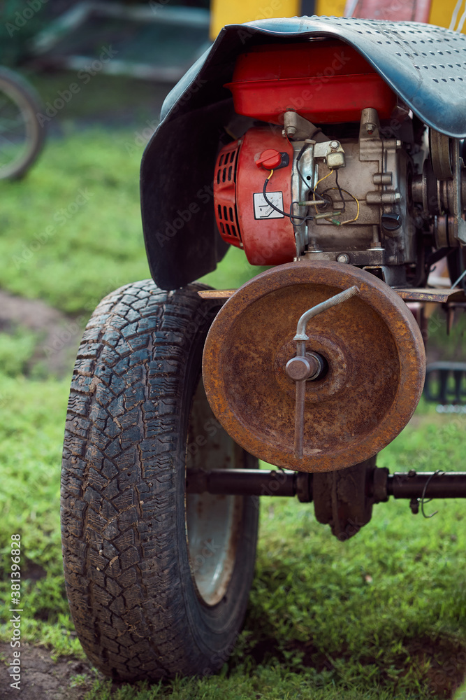 Fototapeta premium Walk-behind tractor on lawn in yard in countryside