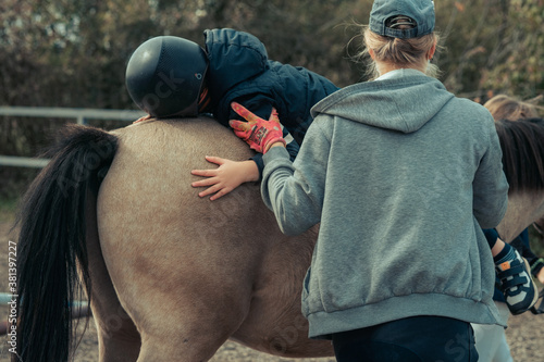 Foto A little boy in turquoise overalls stroking an Icelandic pony horse with a funny forelock