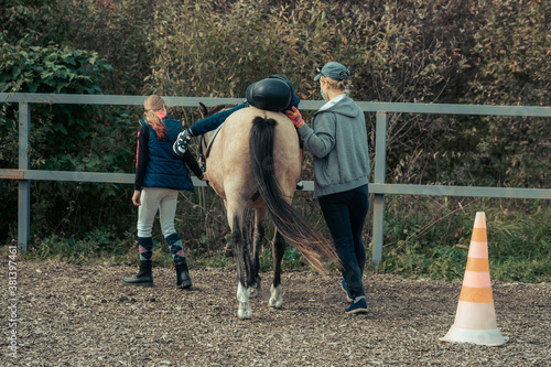 A little boy in turquoise overalls stroking an Icelandic pony horse with a funny forelock. The kid thanks the horse after hippotherapy. Boy horseback riding, performing exercises on horseback