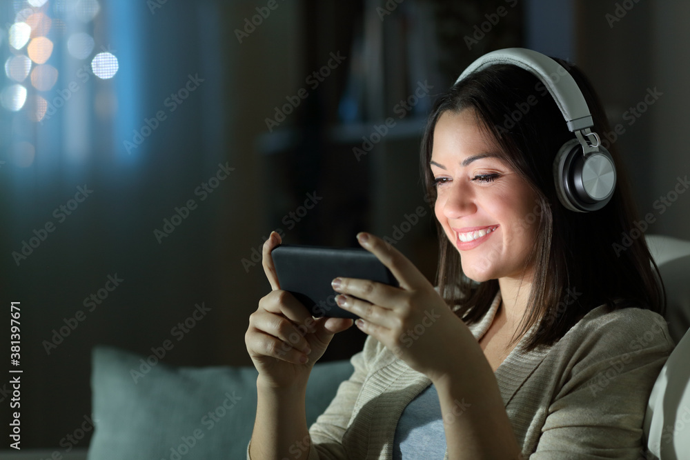 Happy woman watching videos on smart phone in the night Happy woman watching videos on smart phone in the night