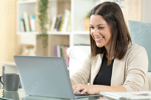Happy woman is using laptop on a table at home