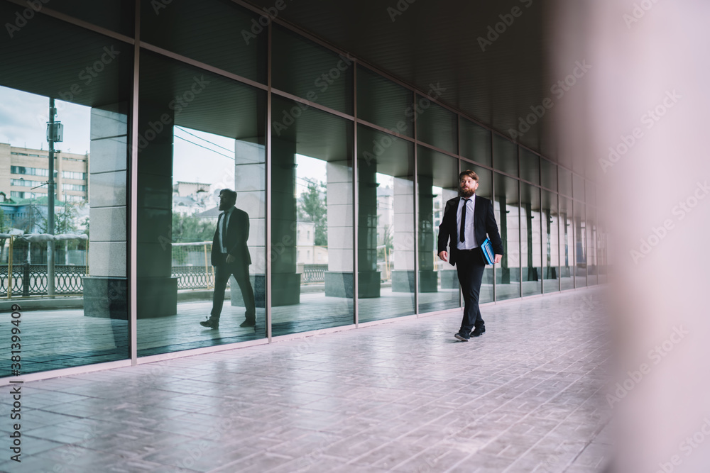 Confident entrepreneur walking along glass building