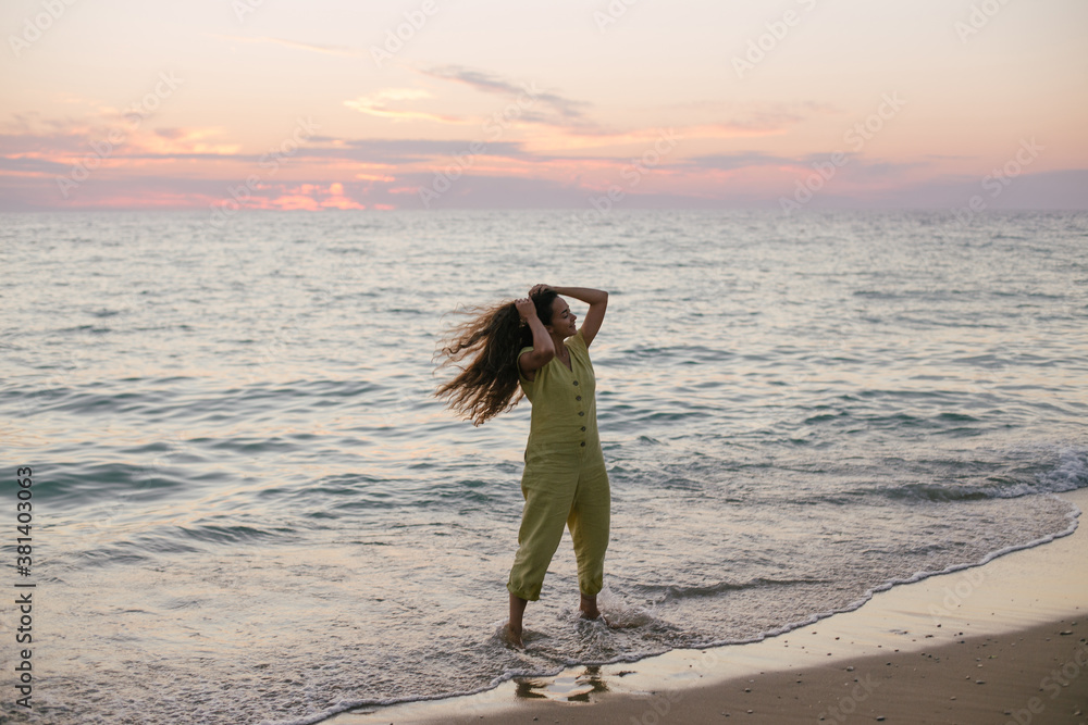 Young beautiful woman posing on a sunset beach.