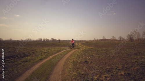 Cyclist. Caucasian sport woman rides along the track in the forest on a spring sunny day. Riding a sportsman girl on a mountain bike on a rural trail in nature. Outdoor sports