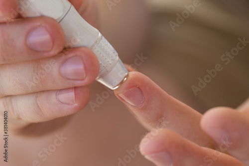 medicine, diabetes, medicine and people concept - close up of a man with a blood glucose meter and a test strip checking blood sugar at home. Diabetes Day, November 14