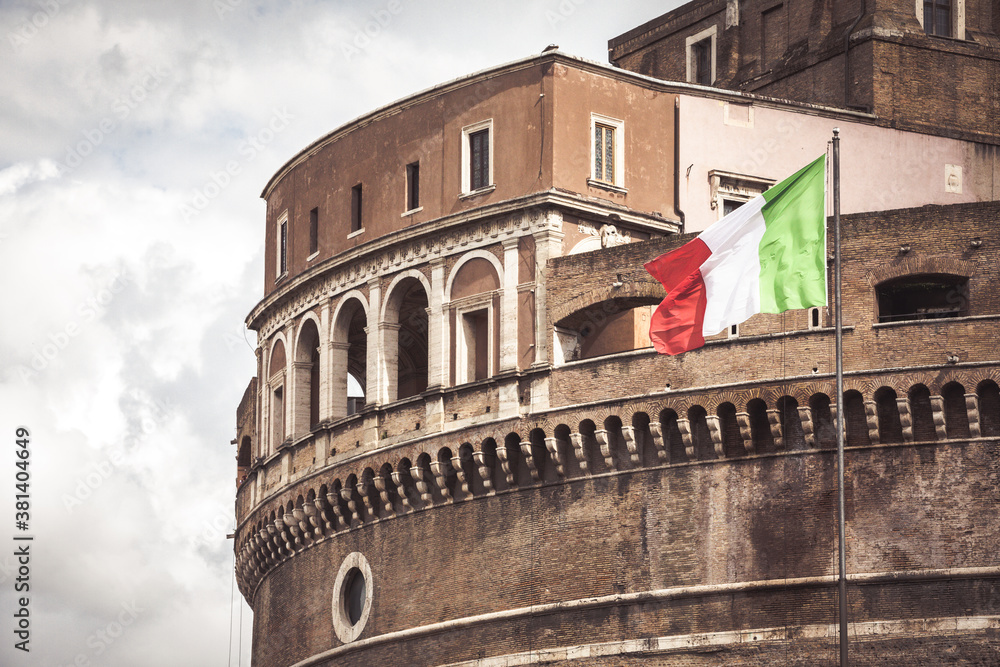 Obraz premium Detail of Castel Sant'Angelo Mausoleum of Hadrian in Rome with Italian flag. Ancient and historic castle monument in Italy. Towering cylindrical building.